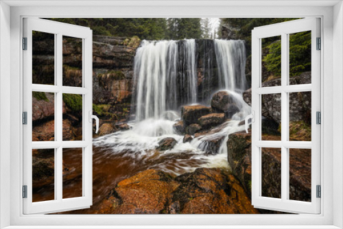 Fototapeta Naklejka Na Ścianę Okno 3D - Amazing waterfall in the middle of mountain forest. River full of water during spring, beautiful flowing mass. Lovely contrast of water and surrounding forest green. Stones and fresh green leaves.