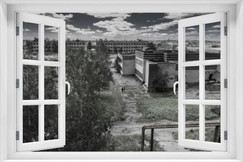 Fototapeta Naklejka Na Ścianę Okno 3D - Landscape of abandoned city, ghost town, with modern, but rusty and ruined empty houses, barracks, and two lonely little figures of rambler adventurers inside. Post apocalypse world