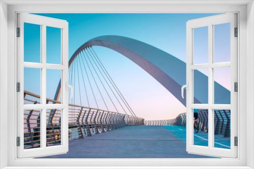 Fototapeta Naklejka Na Ścianę Okno 3D - Young man riding bicycle through Dubai water canal bridge, Beautiful Architecture Design