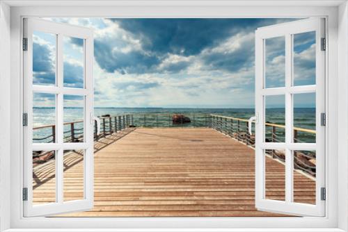 Fototapeta Naklejka Na Ścianę Okno 3D - Perspective view at sea from center of wooden pier made of deck board  with posts and ropes. Dramatic blue sky at beautiful sunny day