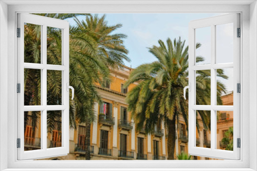 Fototapeta Naklejka Na Ścianę Okno 3D - Palm trees at Plaza Real in Barcelona, Spain with historic building in background with wrought iron balconies.