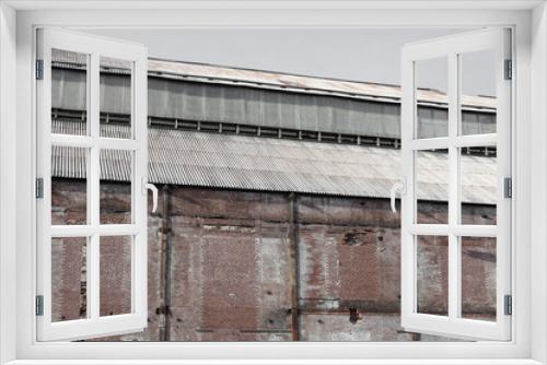 Fototapeta Naklejka Na Ścianę Okno 3D - Weathered wall and steel roof of an old industrial warehouse, horizontal aspect