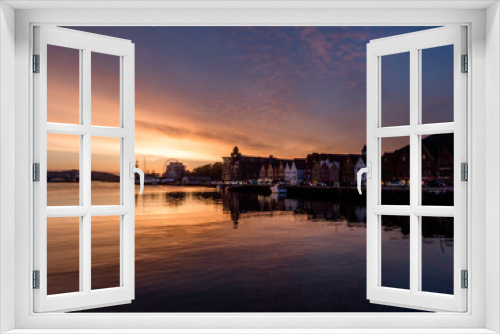 Fototapeta Naklejka Na Ścianę Okno 3D - Beautiful front line of houses build in the port in Bergen, Norway. Soft reflections of houses and boats in the sea. Behind the buildings there is a small hill. Golden hour, sunset in the port.