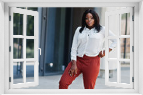 Formally dressed african american business woman in white blouse and red trousers. Successful dark skinned businesswoman.