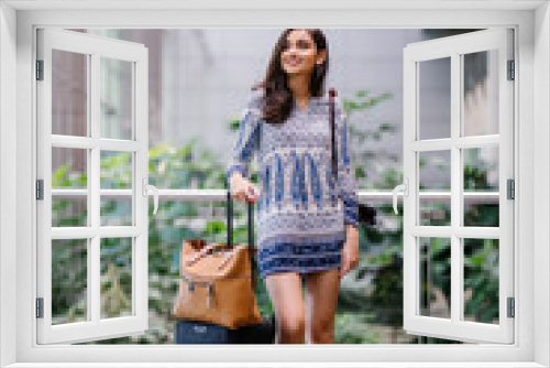 Portrait of a beautiful, young and attractive Indian Asian woman standing next to her travel luggage in a modern airport. She is a tourist in a new country and she is smiling excitedly.