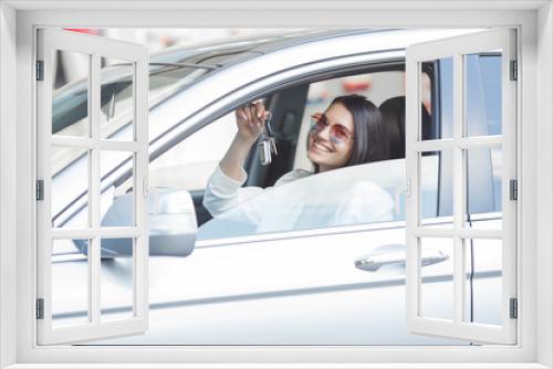 Young attractive woman just bought a new car. female holding keys from new automobile.