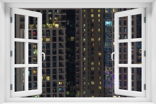Fototapeta Naklejka Na Ścianę Okno 3D - Windows of the multi-storey building with lighting inside and moving people in apartments timelapse.
