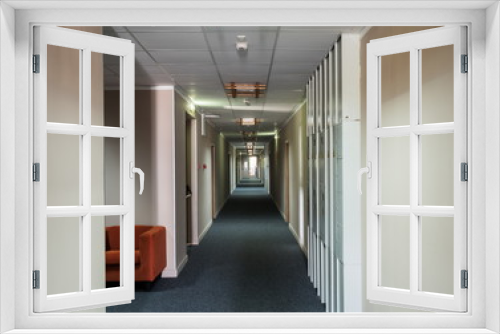 An empty long corridor as in a hospital at the end of bright sun shines through the window