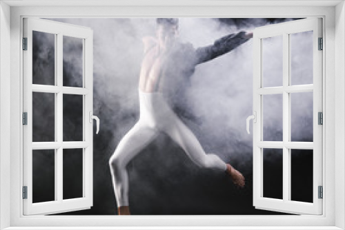 Fototapeta Naklejka Na Ścianę Okno 3D - Young athletic man jumping and dancing near smoke