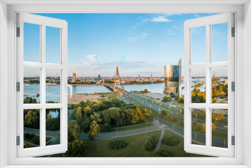 Fototapeta Naklejka Na Ścianę Okno 3D - Panoramic, aerial view over Riga city. Modern buildings, roads, and other infrastructure. Cable bridge leading to iconic old town panorama in vivid sunset colors. 