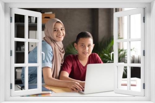 The muslim woman teaching young boy for using laptop,two students doing activity together,at school,blurry light around