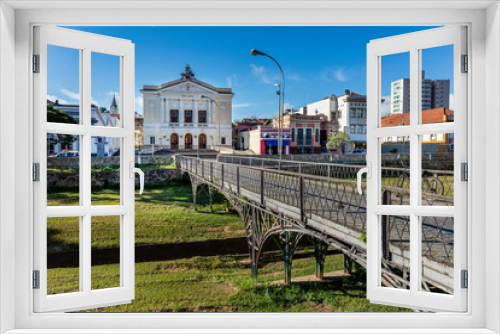 Fototapeta Naklejka Na Ścianę Okno 3D - River with green grass and old buildings of the city hall of the historical and tourist city of Sao Joao del Rey, in the state of Minas Gerais, Brazil.