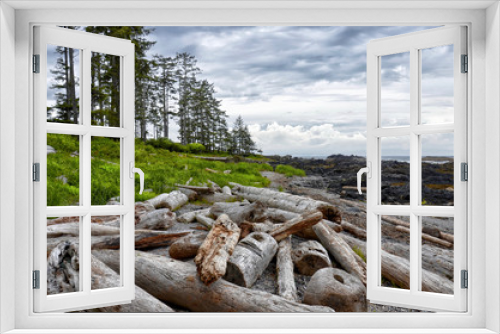 Fototapeta Naklejka Na Ścianę Okno 3D - beautiful pacific coastal seascape with coniferous green forest and drift wood trunks on coastal pebbles on a summer cloudy day with picturesque clouds, Ucluelet, BC, Canada Vancouver Island