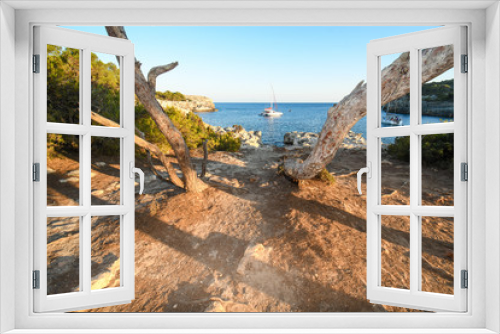 Fototapeta Naklejka Na Ścianę Okno 3D - Typical cove of the Balearic Islands, with foreground trees and boats in the background in Menorca