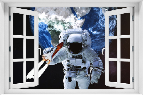 Fototapeta Naklejka Na Ścianę Okno 3D - Astronaut with flying shuttle in his hand in a front of Earth planet of solar system. Science fiction. Elements of the image were furnished by NASA