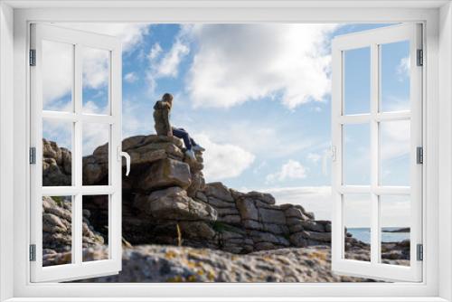 Fototapeta Naklejka Na Ścianę Okno 3D - A girl stands high on stones. Success, happiness, freedom. Ocean and clouds. Beautiful nature landscape in Norway. Amazing scenic outdoors view in North. Travel, adventure, lifestyle. Lofoten Islands