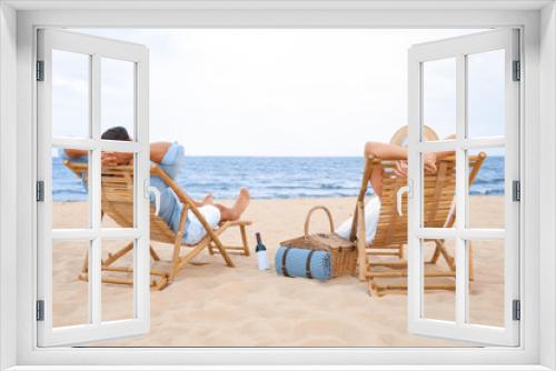 Fototapeta Naklejka Na Ścianę Okno 3D - Happy young couple sitting on deck chairs at sea beach