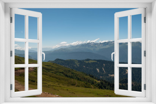 Fototapeta Naklejka Na Ścianę Okno 3D - on alpine meadows of a mountain range at an altitude of more than 2 thousand meters - a view of the mountain peaks, sky and clouds of the ski resort on a sunny summer day in the Caucasus mountains