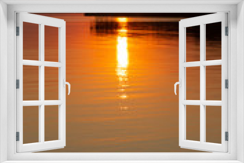 The  vertical photo of golden sunset above the river or sea. Reflection in the water like fire. Seacoast.