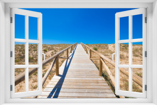 Fototapeta Naklejka Na Ścianę Okno 3D - scenery of footbridge with wooden planks to the blue sky horizon in Natural Park of Trafalgar Cape, next to Canos Meca village (Barbate, Cadiz, Andalusia, Spain)