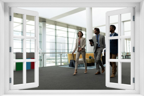 Multi-ethnic business people interacting with each other while walking on office floor