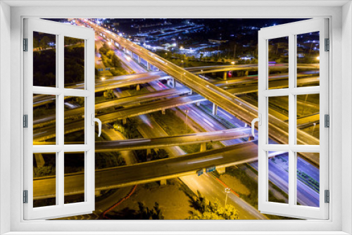 Fototapeta Naklejka Na Ścianę Okno 3D - Aerial view of illuminated road interchange or highway intersection with busy urban traffic speeding on the road at night. Junction network of transportation taken by drone.