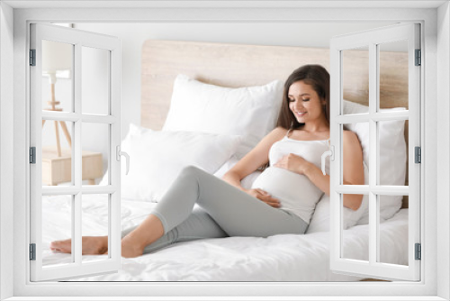 Beautiful young pregnant woman in bedroom