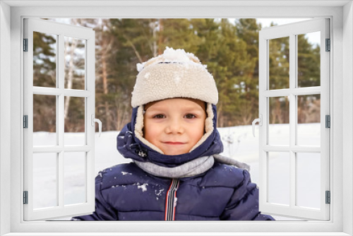 close up portrait of a happy child boy throws snow, snowflakes in the air in cold winter against the background of snowdrifts