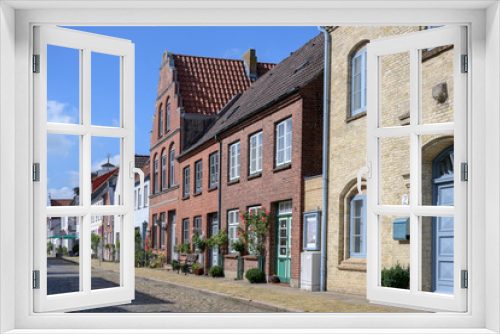 Fototapeta Naklejka Na Ścianę Okno 3D - street with cobblestone pavement and roses  in Friedrichstadt, the beautiful town and travel destination in northern Germany founded by Dutch settlers