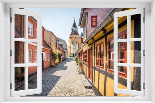 Fototapeta Naklejka Na Ścianę Okno 3D - An alleyway with cobblestones and half timbered houses, leading up to the church in Faaborg