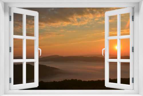 sunset over mountains with fog in the valleys