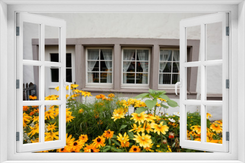 Fototapeta Naklejka Na Ścianę Okno 3D - beautiful yellow flowers in front of simple white house with door and 