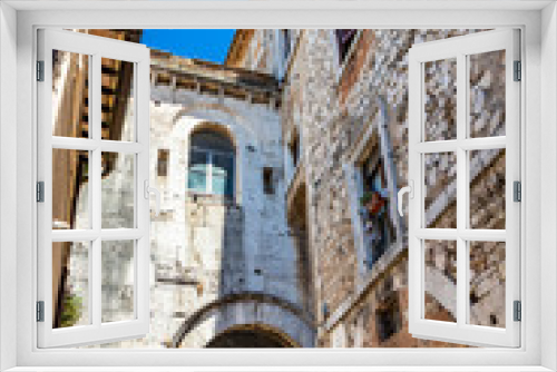 Fototapeta Naklejka Na Ścianę Okno 3D - A characteristic glimpse of the city of Amelia, in Umbria. The cobbled alley, the stone and brick walls of the old houses in the historic center. A small gallery with arch.