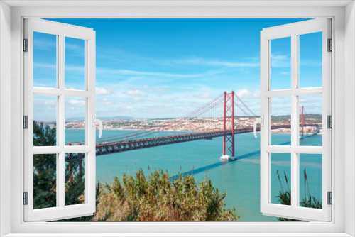 Fototapeta Naklejka Na Ścianę Okno 3D - The 25 de Abril Bridge on beautiful blue sky sunny day. The bridge connecting the city of Lisbon to the municipality of Almada. Tejo river, Lisbon, Portugal