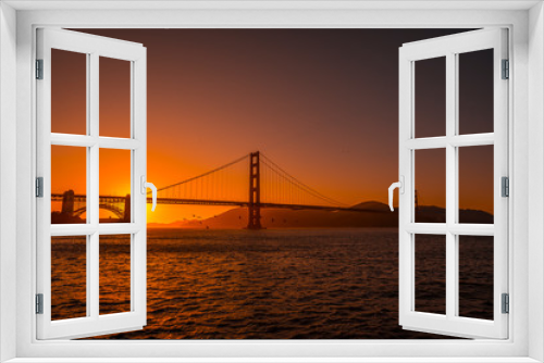 Fototapeta Naklejka Na Ścianę Okno 3D - Red sunset at the Golden Gate of San Francisco with the sun hiding on the bridge. United States