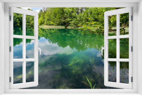Fototapeta Naklejka Na Ścianę Okno 3D - Azure coloured lake with reed growing along the shore deep in the dense forest of the Plitvice Lakes National Park in Croatia