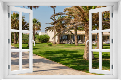 Fototapeta Naklejka Na Ścianę Okno 3D - Path with palms leading to the hotel located at the azure mediterranean sea and surrounded by a beautiful nature of Cyprus. Ayia Napa.