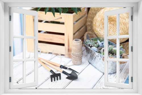 Fototapeta Naklejka Na Ścianę Okno 3D - Gardening tools, plants and straw hat on white wooden table, closeup