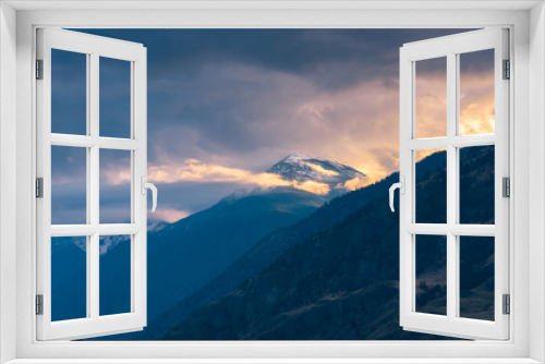 Fototapeta Naklejka Na Ścianę Okno 3D - Snow-capped mountain glowing in sunset light with dramatic clouds and fog in Cawston, British Columbia, Canada