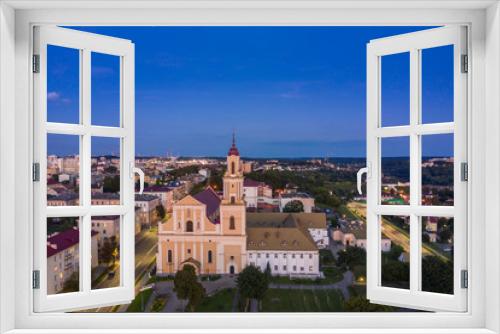 Holy Cross Church And Traffic In Mostowaja And Kirova Streets At Evening In Night Illuminations Lights. Sunset Sky. Grodno city in Belarus