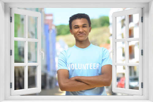 Young mixed-race male volunteer with folded arms smiling on cam outdoor, help