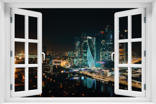 Fototapeta Naklejka Na Ścianę Okno 3D - Picturesque aerial panorama of Moscow City Business Center on the night with bright glittering lights of buildings, streets and traffic. Camera slowly moves away showing amazing cityscape.