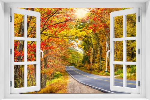 Fototapeta Naklejka Na Ścianę Okno 3D - Beautiful autumn road winding through splendid fall foliage in New England. Sun rays peeking through golden trees.