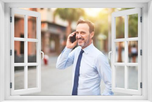 Middle age handsome businessman talking on the smartphone smiling