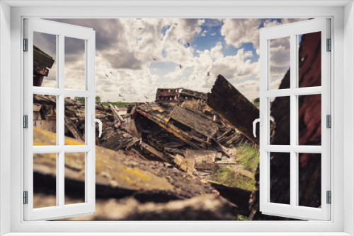 Fototapeta Naklejka Na Ścianę Okno 3D - A derelict shipwreck with dark clouds and birds flying over it, seen in King's Lynn, Norfolk, England, UK