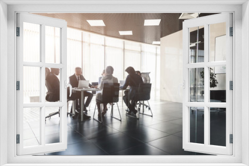 Silhouettes of people sitting at the table. A team of young businessmen working and communicating together in an office. Corporate businessteam and manager in a meeting