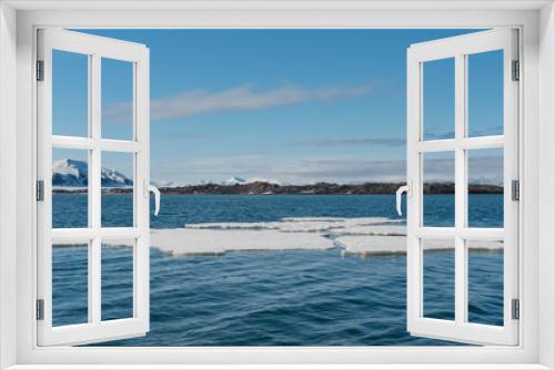 Fototapeta Naklejka Na Ścianę Okno 3D - Blocks of ice floating in an arctic fjord on a sunny day with blue sky and snowy mountains in the distance in Svalbard