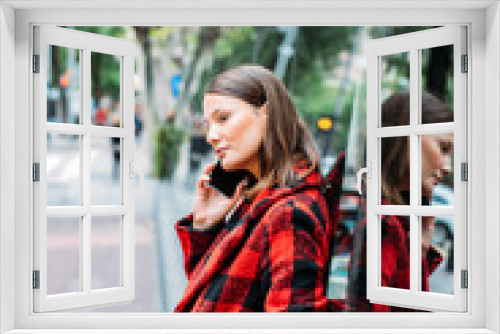 pretty young woman standing on glass on the street using smartphone