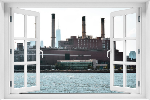 Fototapeta Naklejka Na Ścianę Okno 3D - Office, apartments and industrial chimneys buildings in the skyline at sunset, from Hudson river. Pollution and industry concept. Manhattan, New York City, USA.