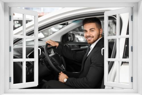 Happy male buyer sitting in new car